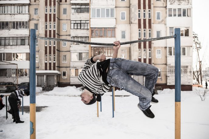 A young boy demonstrates acrobatic sports on a fixed bar in a playground of the Baykivskyi area of the city (built by architects from Azerbaidjan.