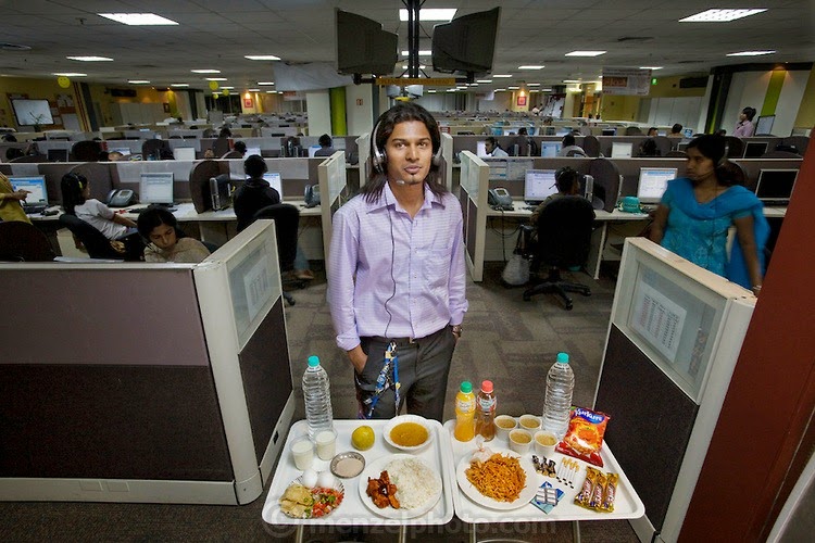 Shashi Kanth, a call center worker, with his day's worth of food in his office at the AOL call center in Bangalore, India. (From the book What I Eat: Around the World in 80 Diets.) He is 23 years of age; 5 feet, 7 inches; and 123 pounds. Like many of the thousands of call center workers in India, he relies on fast-food meals, candy bars, and coffee to sustain him through the long nights spent talking to Westerners about various technical questions and billing problems. He took a temporary detour into the call center world to pay medical and school bills but finds himself still there after two years, not knowing when or if he will return to his professional studies. MODEL RELEASED.