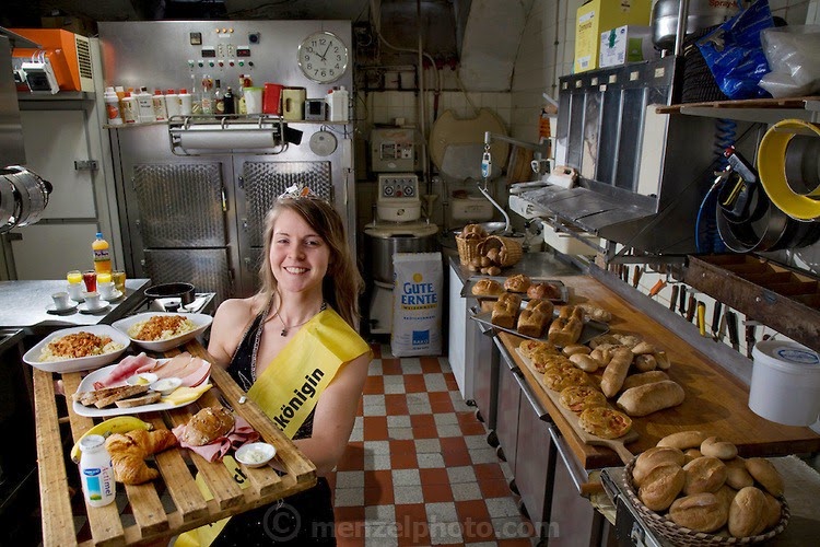 Robina Weiser-Linnartz, a master baker and confectioner with her typical day’s worth of food in her parent’s bakery in Cologne, Germany. (From the book What I Eat; Around the World ion 80 Diets.) The caloric value of her day's worth of food in March was 3700 kcals. She is 28 years of age; 5 feet, 6 inches tall; and 144 pounds. She’s wearing her Bread Queen sash and crown, which she dons whenever she appears at festivals, trade shows, and educational events, representing the baker’s guild of Germany’s greater Cologne region. At the age of three, she started her career in her father’s bakery, helping her parents with simple chores like sorting nuts. Her career plan is to return to this bakery, which has been in the family for four generations, in a few years. She will remodel the old premises slightly to allow customers the opportunity to watch the baking process, but plans to keep the old traditions of her forebears alive. MODEL RELEASED.
