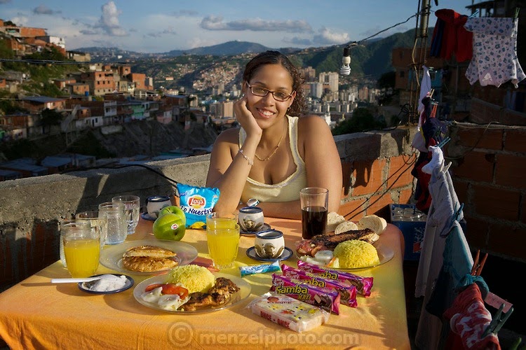 Katherine Navas, a high school student, on the roof of her family’s home in a barrio in Caracas, Venezuela with her typical day’s worth of food. (From the book What I Eat: Around the World in 80 Diets.) The caloric value of her typical day's worth of food in the month of November was 4,000 kcals. She is 18 years of age; 5 feet, 7 inches tall; and 157 pounds. Unlike housing in most of the developed world, the higher the house, the cheaper the rent in the dangerous Caracas barrios. Those living at the top of the steep hillside have to travel the farthest to reach services, shops, and the main street, a trip normally made only in the daylight hours. MODEL RELEASED